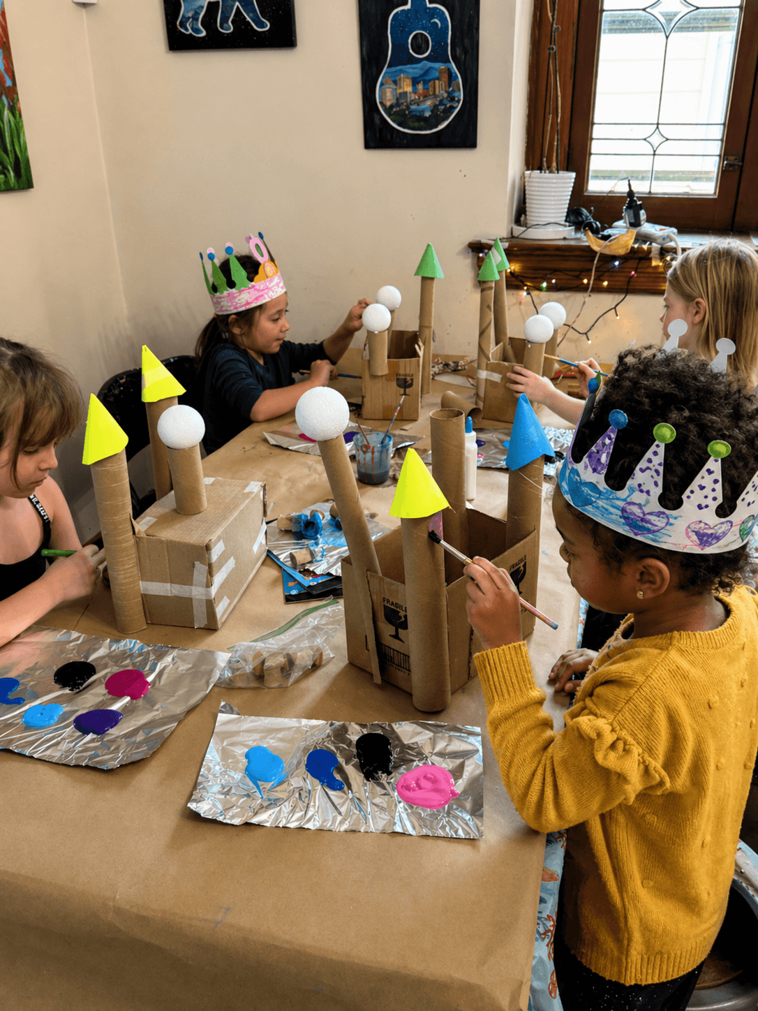 Kids painting cardboard castles together at an art birthday party