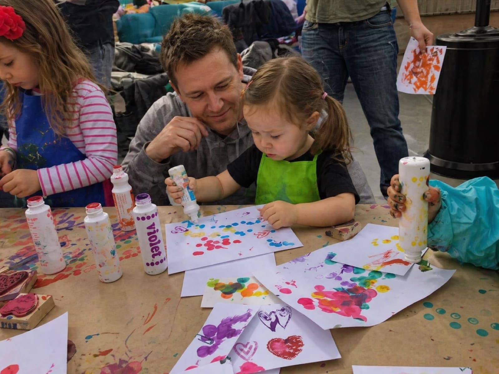 A father and toddler doing dot painting together at a family art event