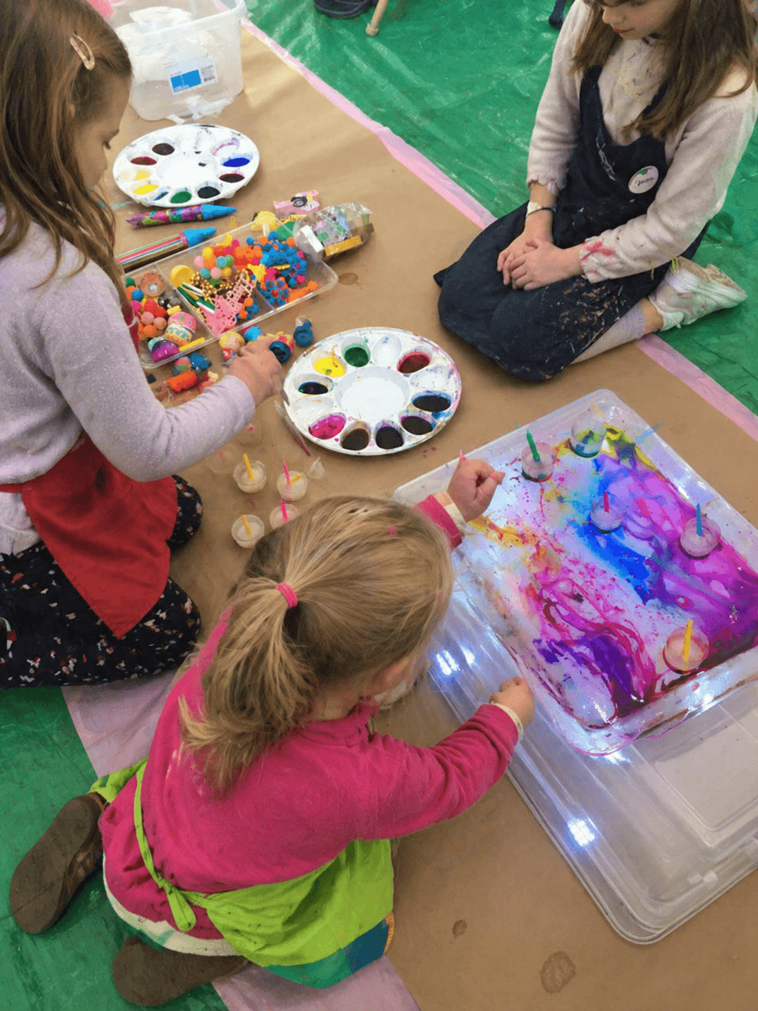 Three small girls exploring a sensory paint tray together
